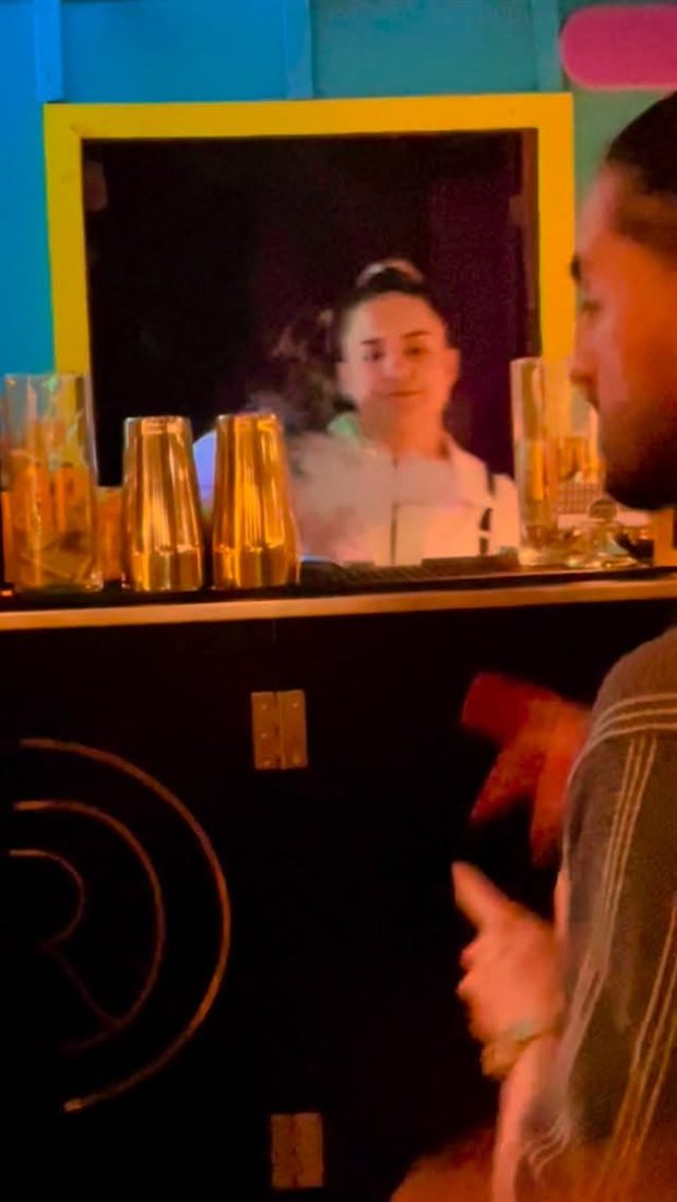 Bartender preparando cócteles de noche detrás de la barra negra con logo dorado