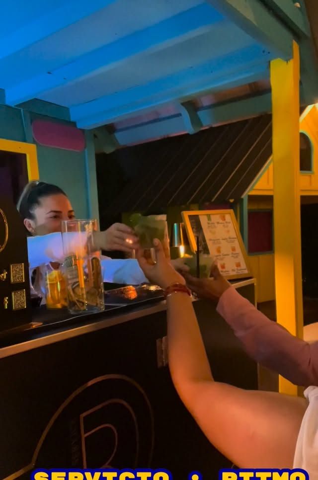 Bartender entregando un cóctel a una invitada durante una fiesta nocturna